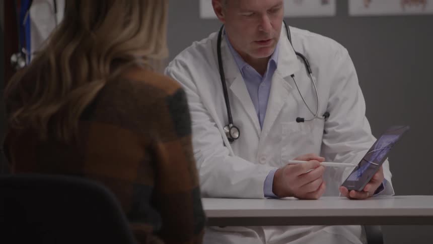 Medical consultation with doctor showing information on tablet to patient in a modern clinical setting