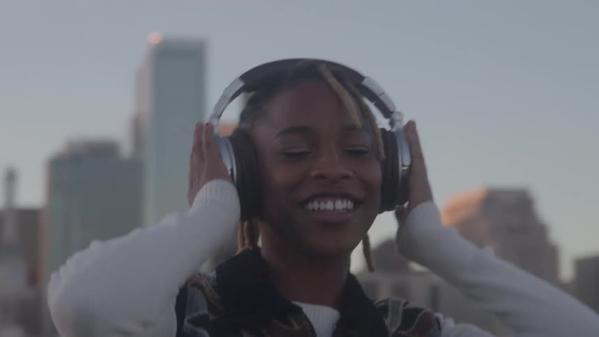 The woman listens to music in front of the big city