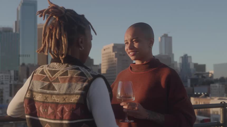 A young black couple conversing while standing outdoors at a balcony in a metropolitan city during daytime