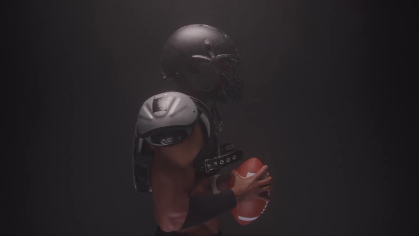 American football player grips the ball with focused expression