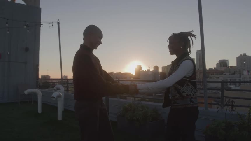 Couple shares intimate moment at sunset on urban rooftop foreheads touching in a serene atmosphere