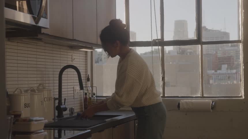 The woman is washing dishes in the sink