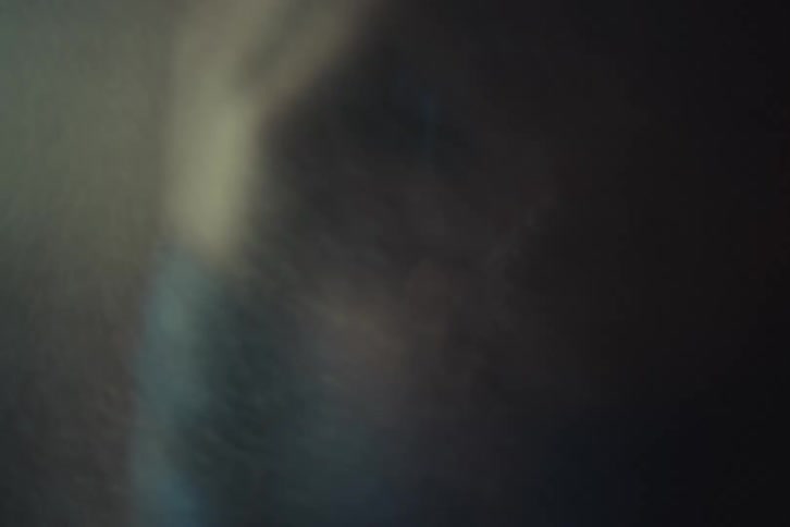 Person with hand on face appears amid soft mist and diffused light