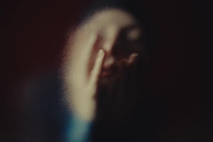 Abstract person with hand over face stands out amid soft shadows and diffused light