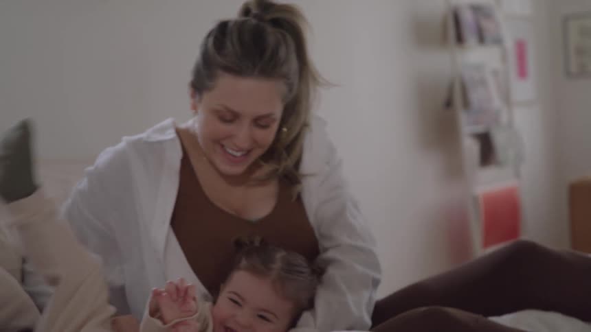 Mother and daughter have fun together on the bed in a moment of affection and laughter