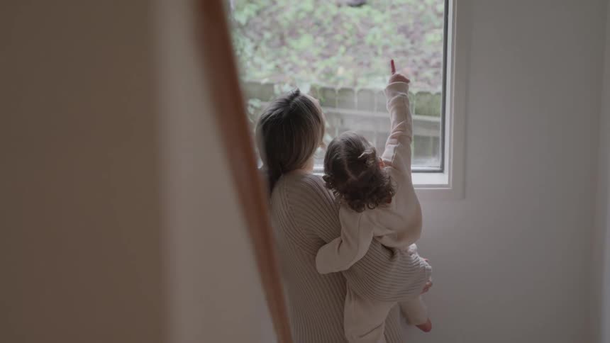 Adult holding small child near window overlooking a green outdoor area