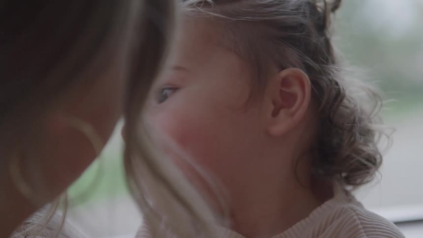 Child smiles and interacts closely with an adult in an affectionate moment