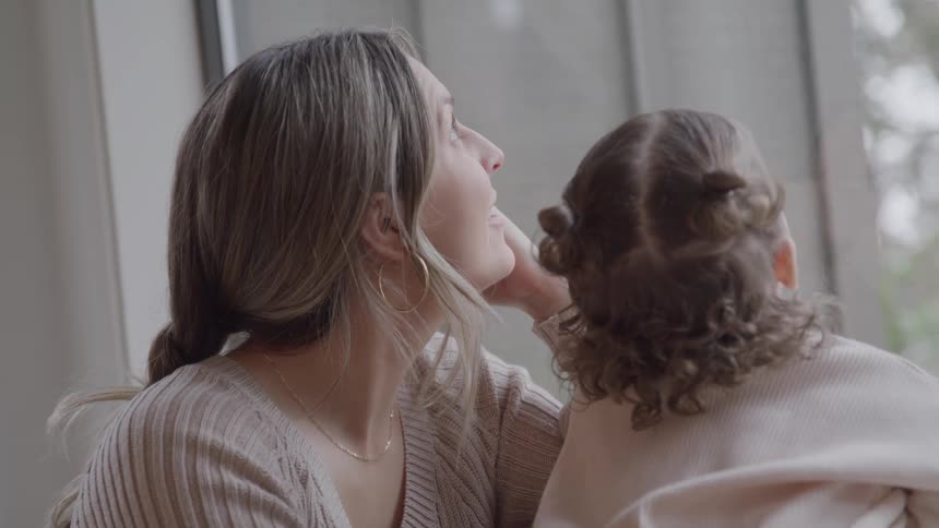 Woman and child watch something through the window sharing a calm moment together