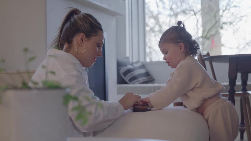 Mother watches her daughter as she plays intently in a bright setting
