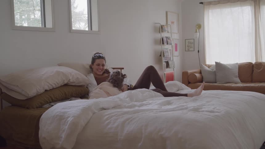 Two people resting on a bed in residential setting with natural lighting