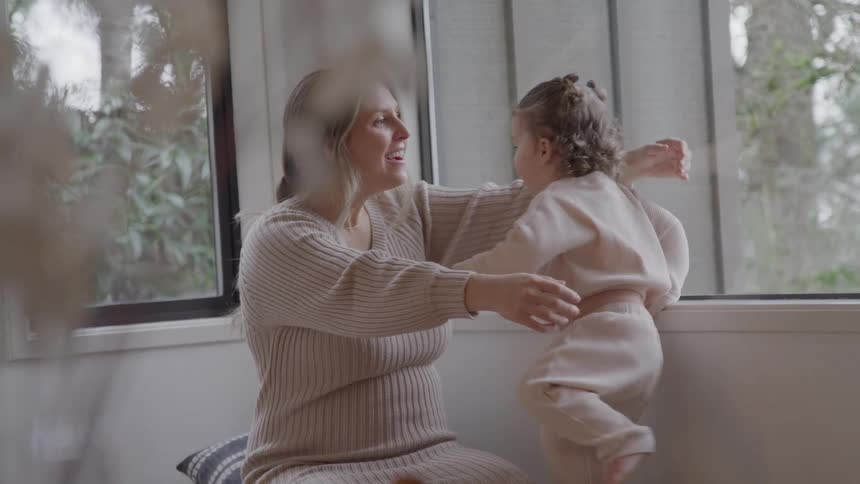 Woman hugs her daughter lovingly by the window in an affectionate moment