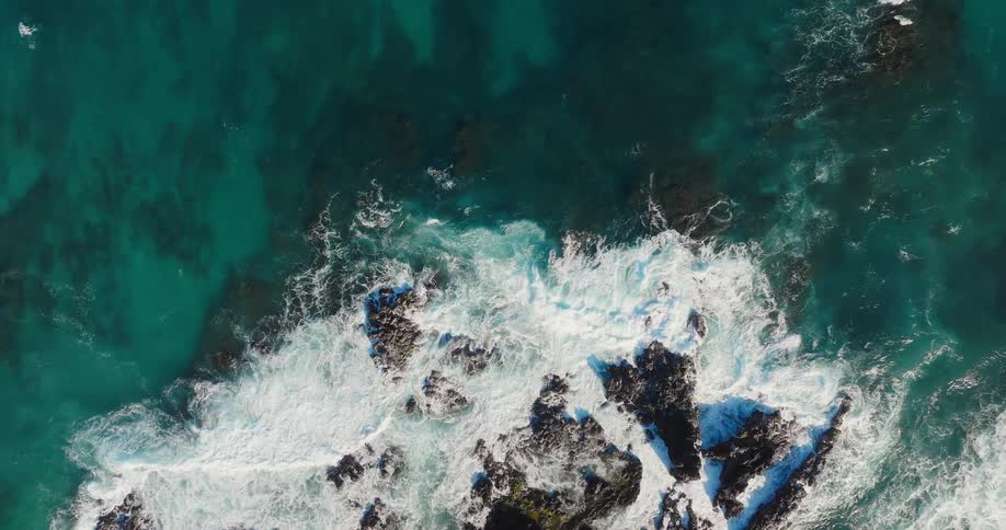 The waves crash on the rocks of the shore