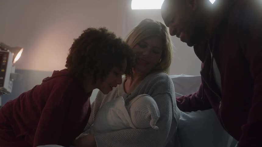 The girl kisses the newborn in the hospital