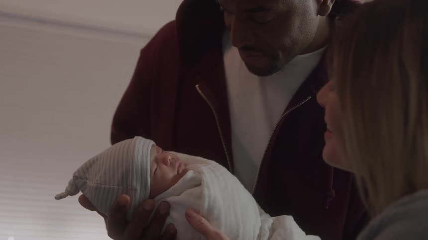 Parents look at the newborn in their arms with tenderness and admiration