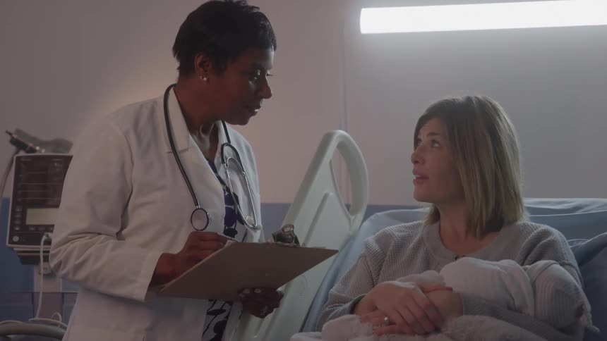 The doctor talks with a mother holding her baby