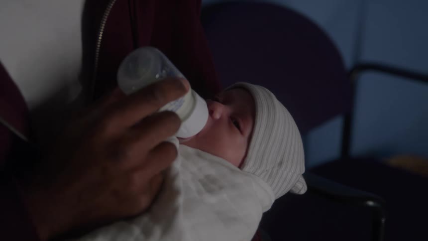 The father is feeding the newborn with a bottle