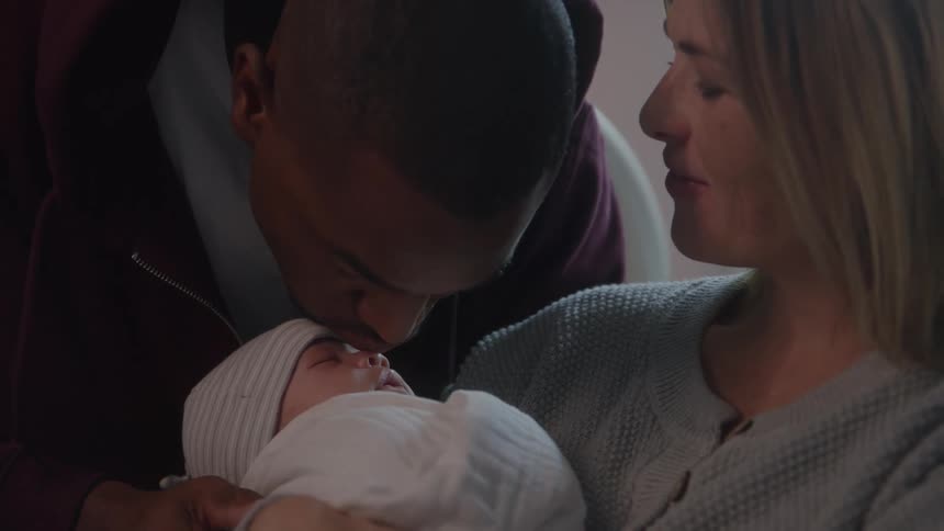 Parents gaze at their newborn with affection and tenderness in their first moments as a family