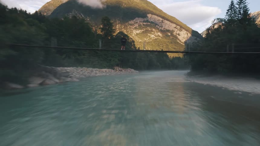 The hiker stands on the small bridge over the stream