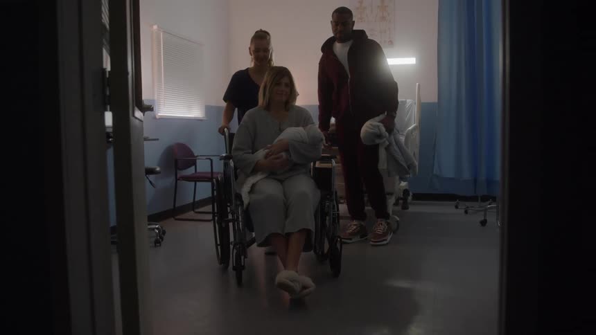 The nurse pushes the mother and newborn in a wheelchair