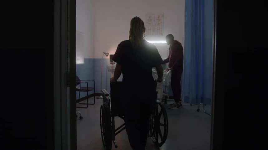 The nurse pushes the wheelchair into the hospital room