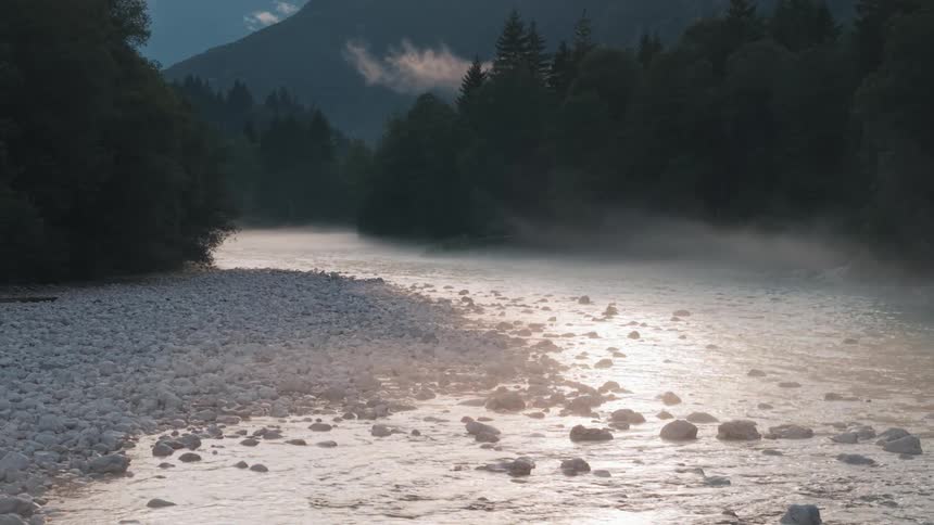 Calm waters reflect the soft light along the rocky riverbed