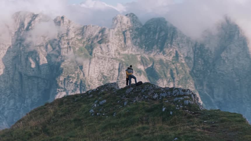 Person contemplates the mountainous landscape shrouded in clouds