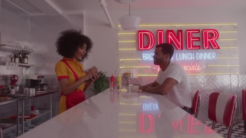 Waitress chats cheerfully with a customer in a retro diner