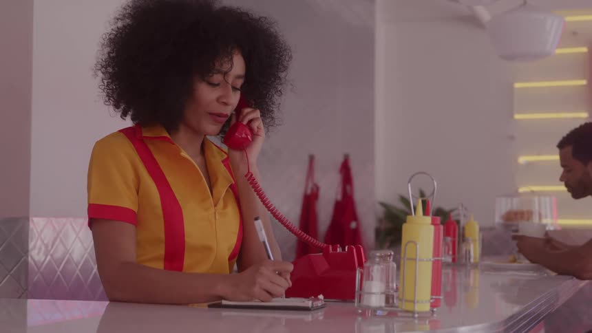 Female server taking an order over the phone at a retro diner