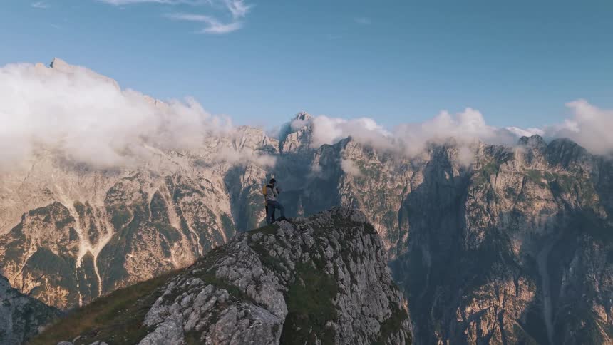 Person enjoys the view among clouds at the top of a mountain