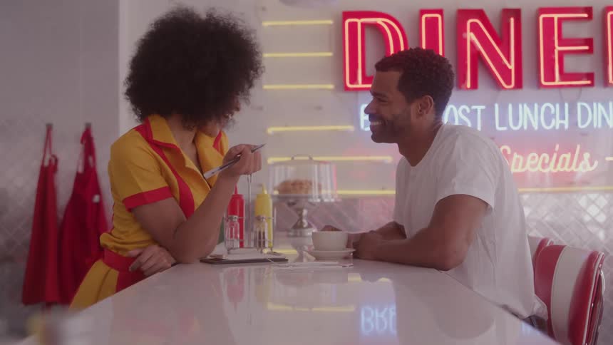 Waitress smiles while talking with a customer at the diner counter
