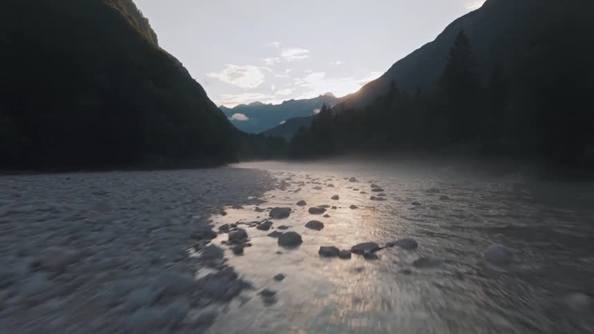 Dawn light reflects on the calm waters between mountains