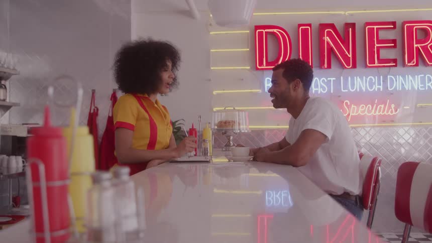 Waitress takes an order smiling while talking with a customer at the counter