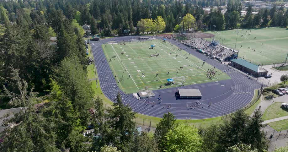 Runners warm up on a track at an outdoor sports complex hosting a track and field event