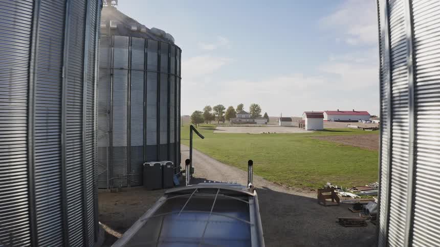 Metal silos with grain transport system and truck parked between the structures