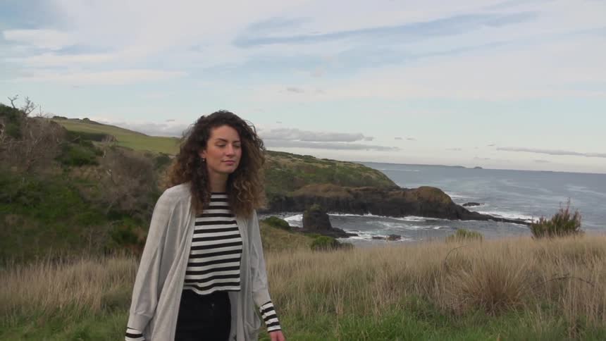Woman walks the hills above a shoreline