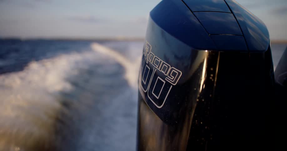 Close up of the outboard engine of a moving speedboat at sea during daytime