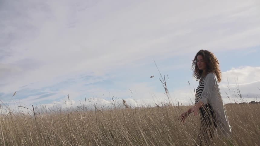 A woman walking in a field on a cloudy day