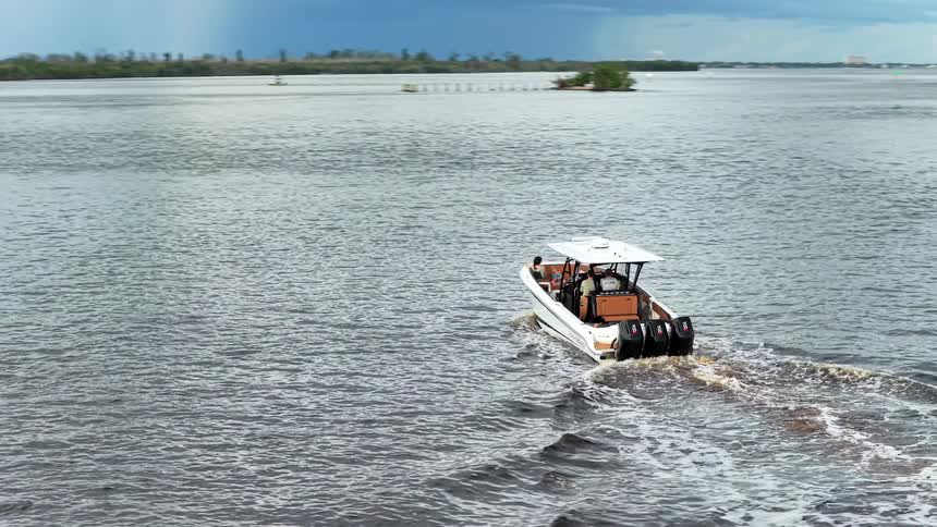 Speedboat sails through calm waters under a partly cloudy sky