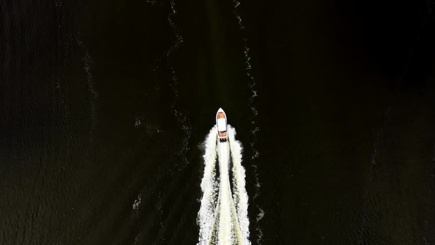 Speedboat moves swiftly leaving a trail of foam on the dark water
