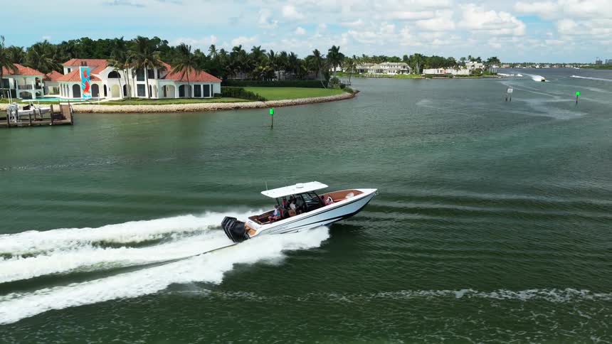 White speedboat cruising through canal surrounded by redroofed houses and palm trees