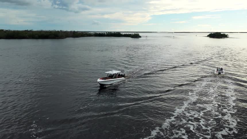 Motorboats crossing coastal waters with islands in the background under partly cloudy sky