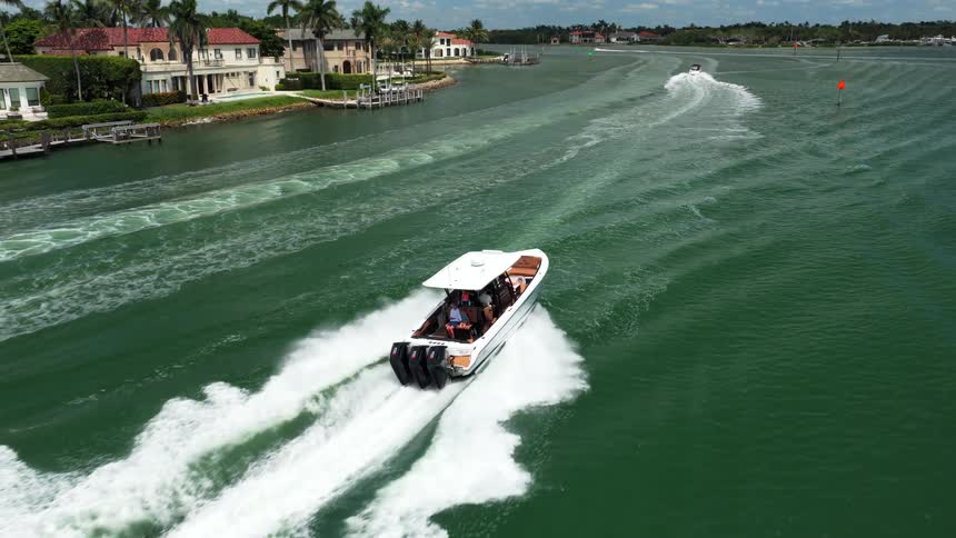 Speedboat leaves a trail of foam at high speed in a canal lined with houses