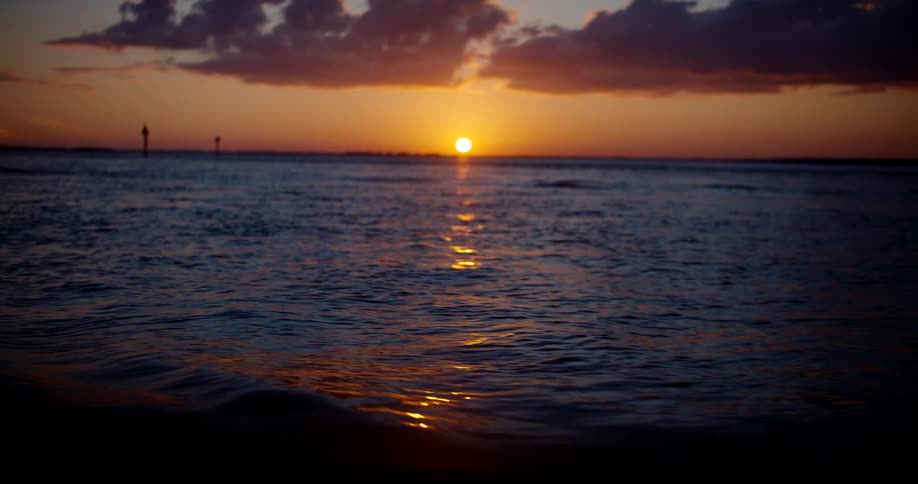 An ocean view at sunset with gentle waves creating a light ripple effect across the waters surface