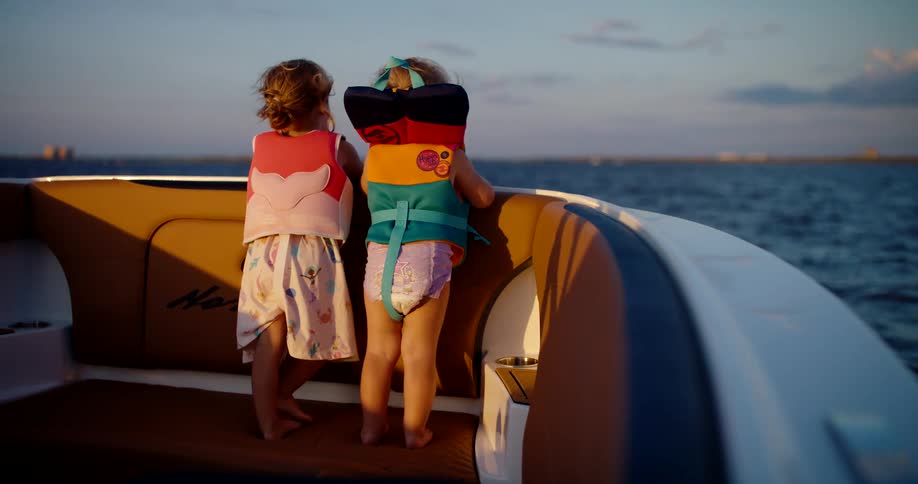 Children wearing life jackets watch the sea aboard a boat