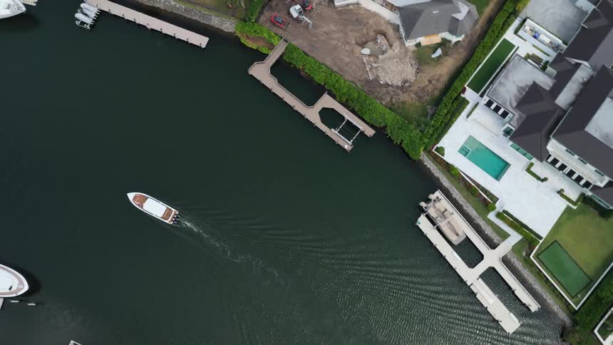 Birds eye view of boat cruising through waterway with waterfront homes