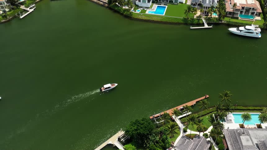Boat sailing in a canal surrounded by houses and pools