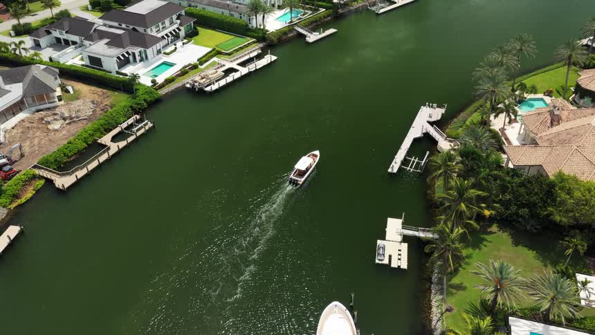 Aerial of boat crusing through waterway in the harbor with waterfront homes