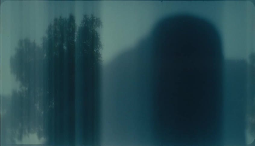 Closeup of a glass door partly open with blurred trees behind