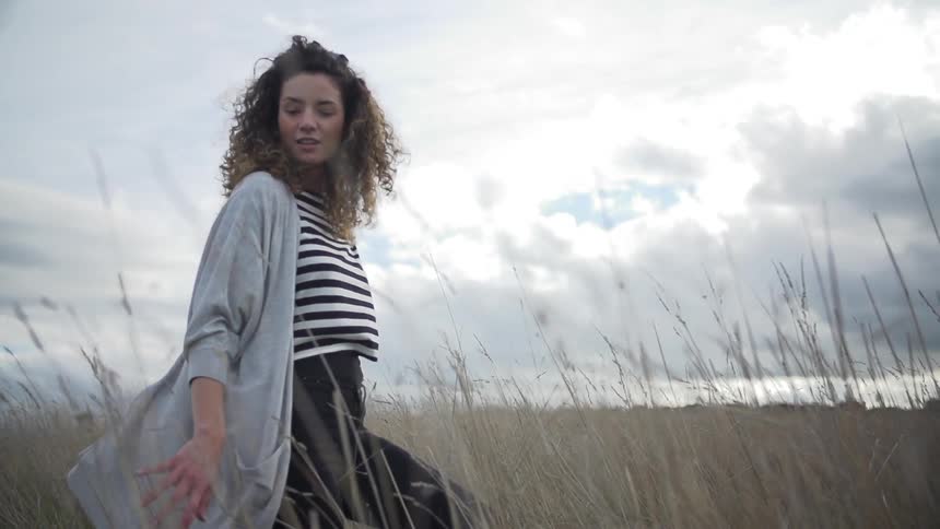 Woman walks on a field on a cloudy day
