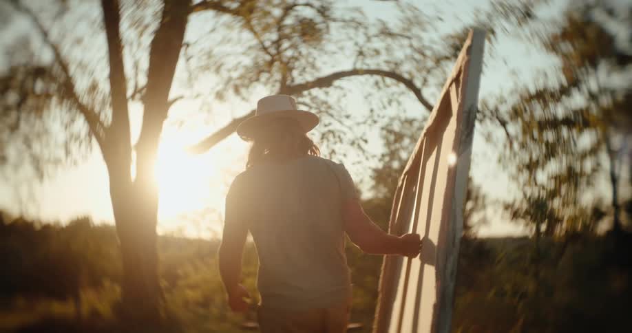 Person wearing a hat carries a large canvas outdoors under the golden sunset light